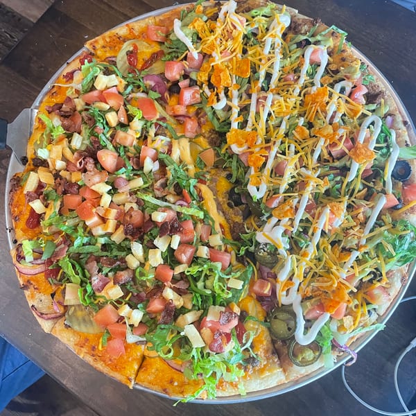 Loaded half-and-half pizza featuring cheeseburger toppings with bacon and taco toppings with jalapeños.