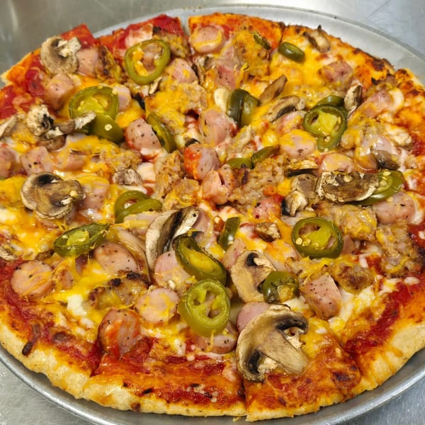 Whole pizza with sausage, mushrooms, jalapeños, and melted cheese on a metal tray.
