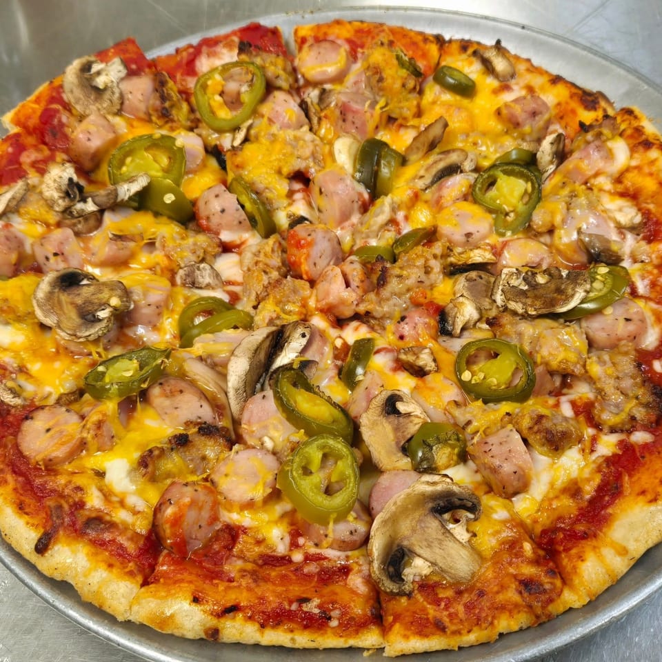 Whole pizza with sausage, mushrooms, jalapeños, and melted cheese on a metal tray.